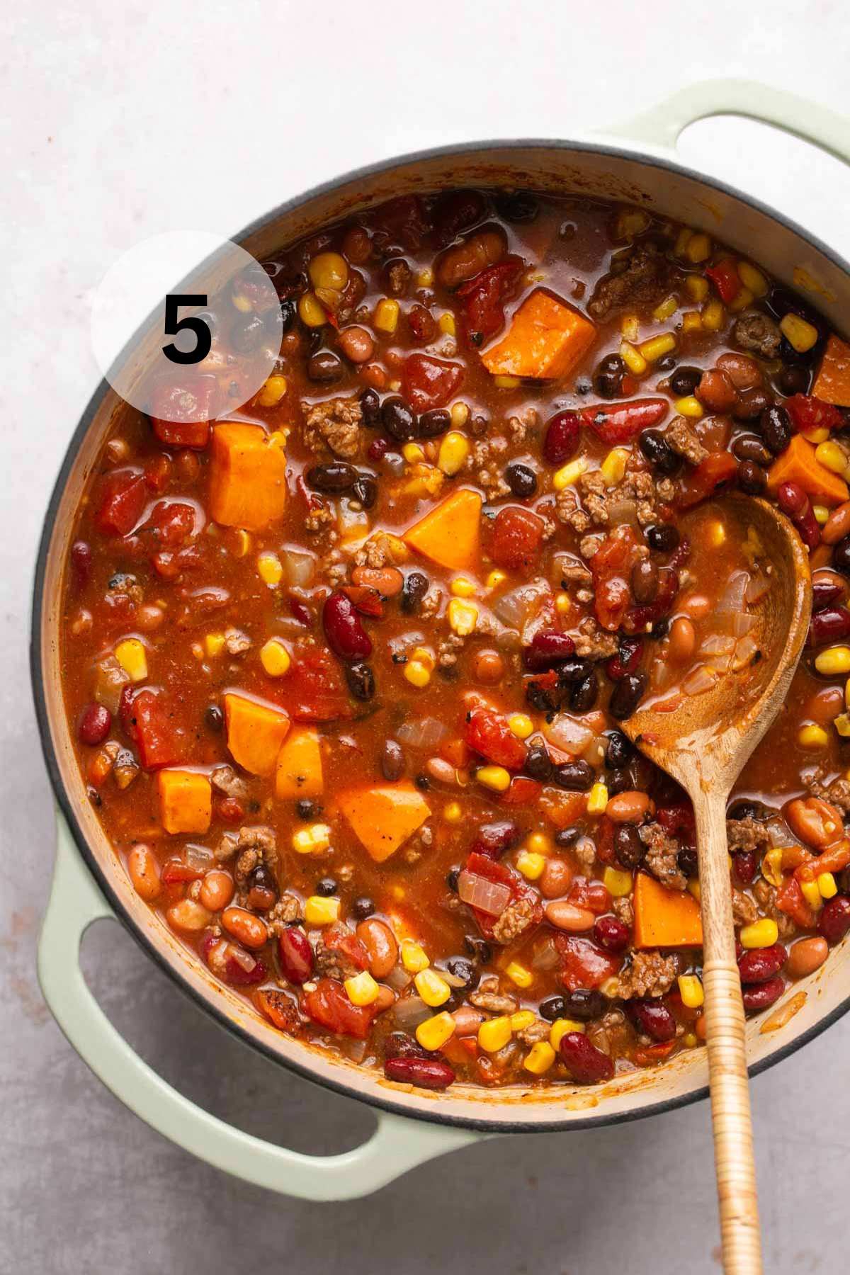 Stirring in beans and corn into chili.