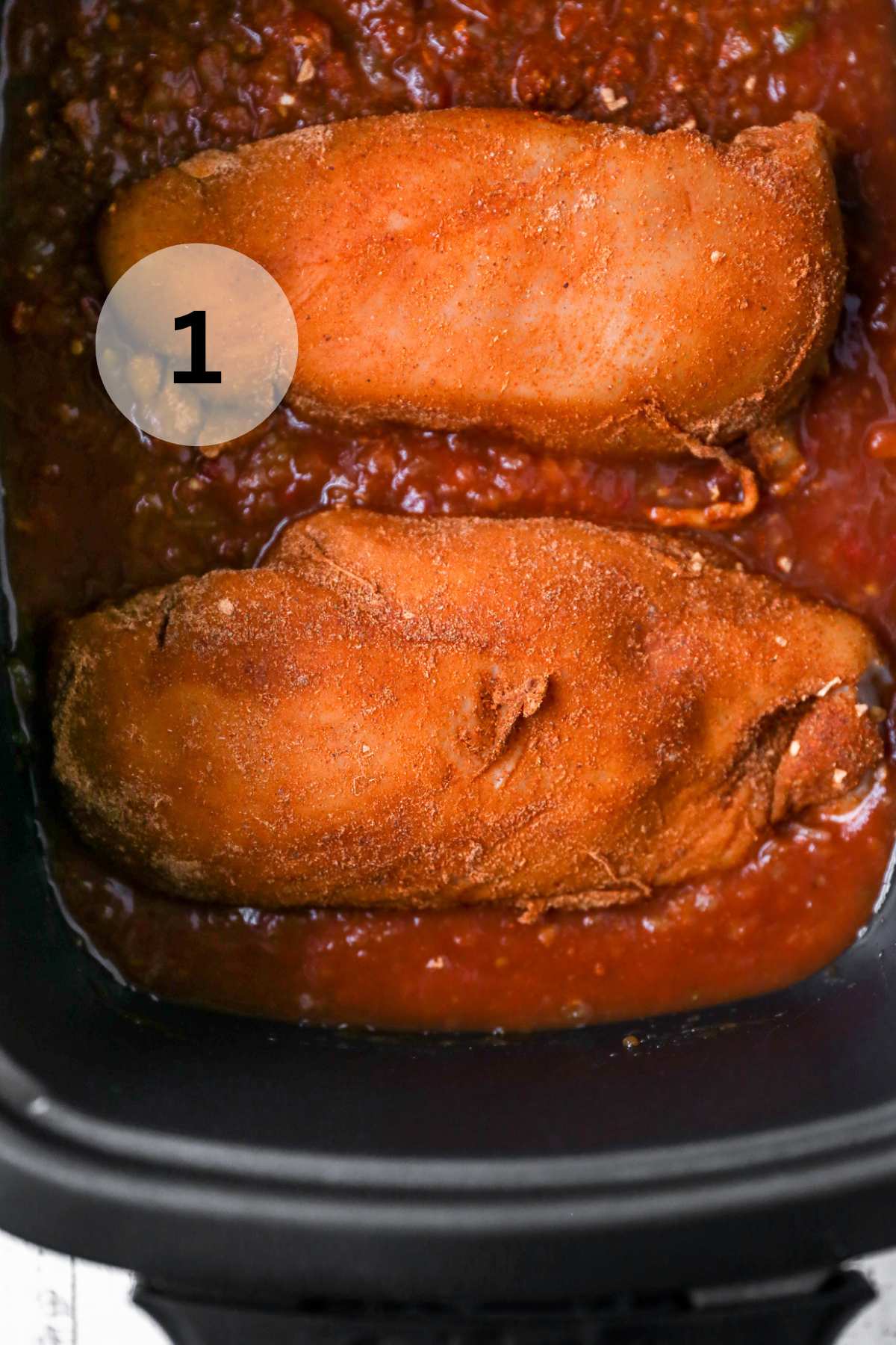Seasoning rubbed on two chicken breasts in a crockpot.