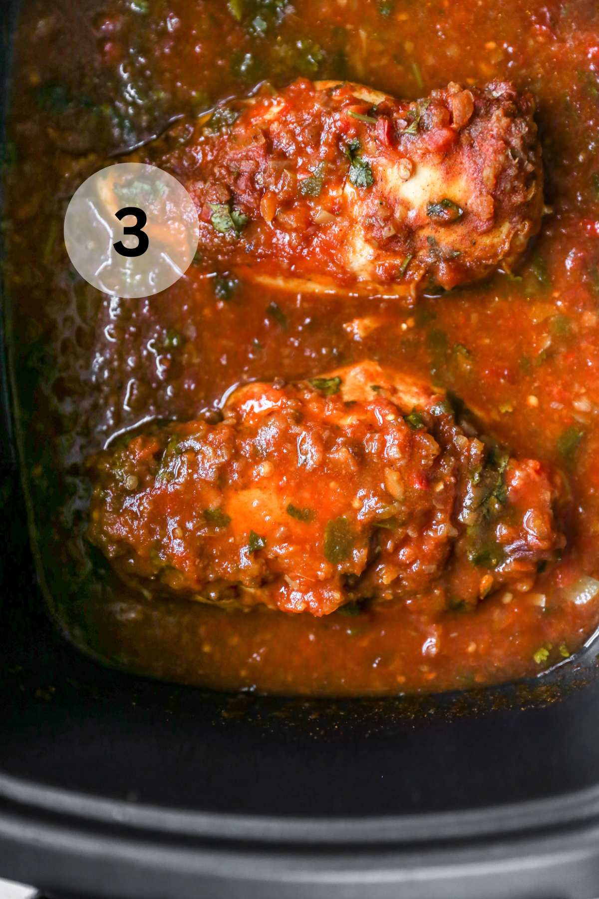 Cooked crockpot salsa chicken in a slow cooker.