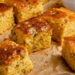 Pieces of Mexican cornbread drizzled on parchment paper.