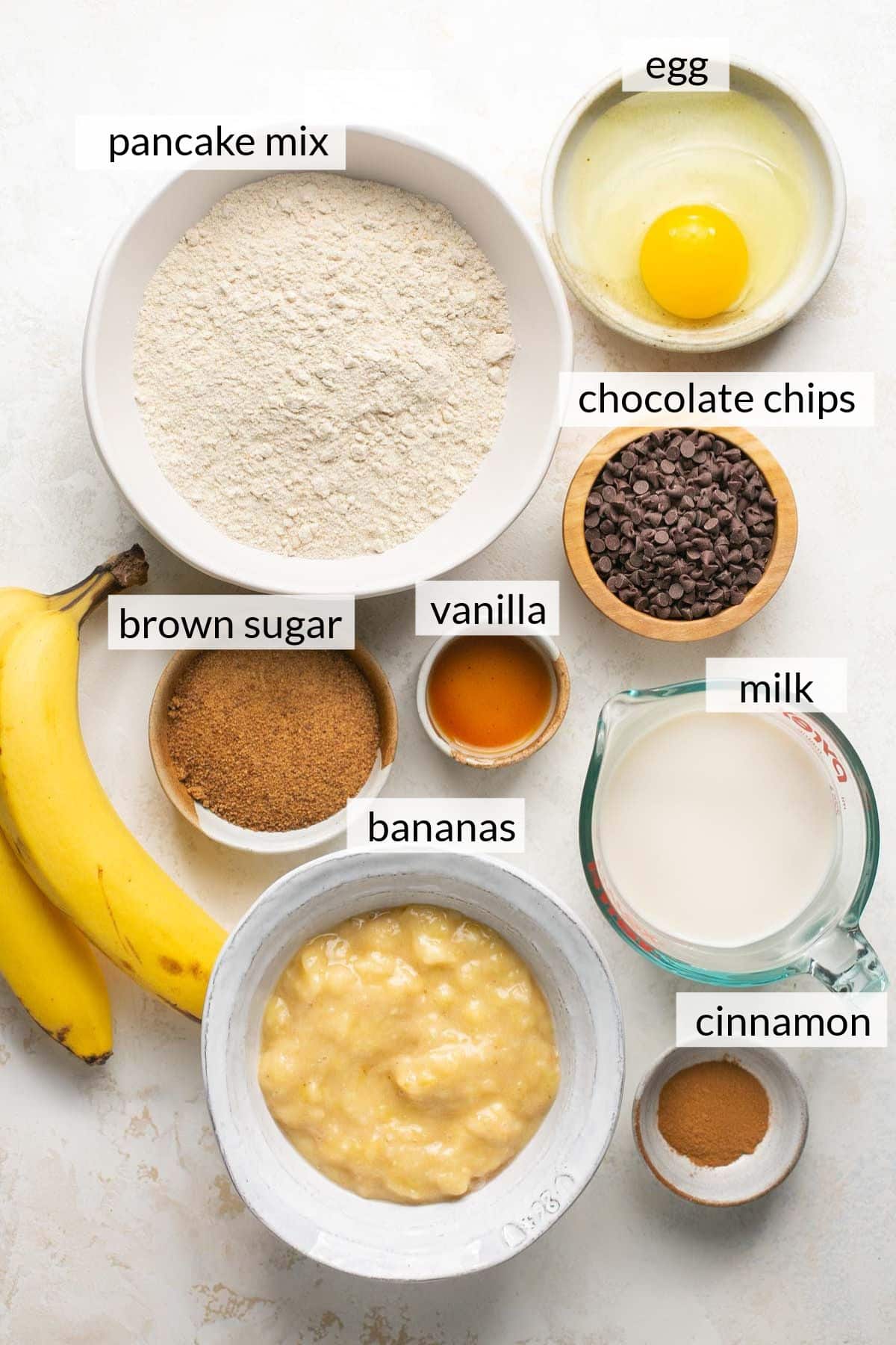 Mashed bananas, egg, milk, pancake mix, vanilla, sugar and cinnamon in small bowls.