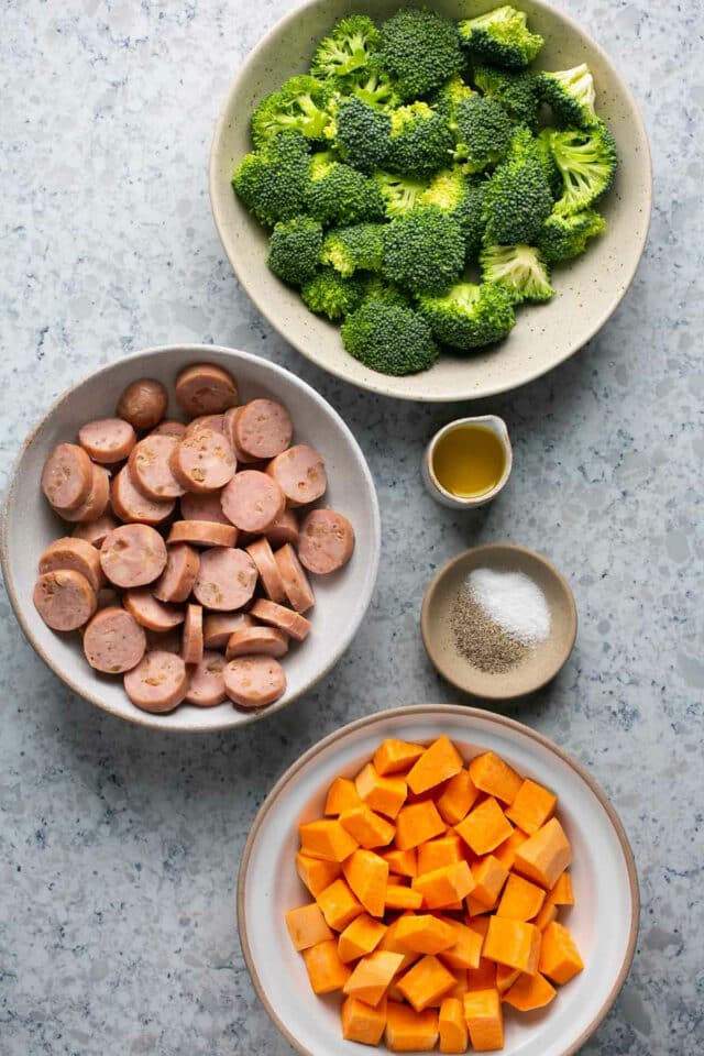 Broccoli, sausage and cubed sweet potato divided into bowls.