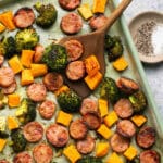 Sliced chicken sausage and veggies on a sheet pan.
