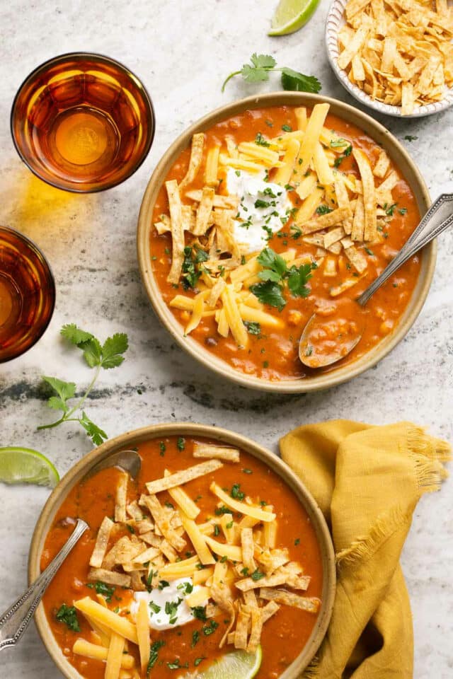 Bowls of chicken enchilada soup topped with tortilla strips.