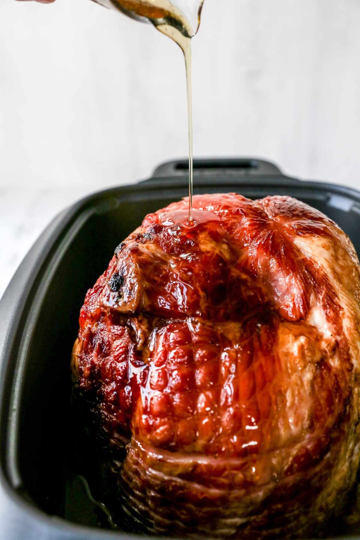 Pouring honey over ham in a slow cooker.