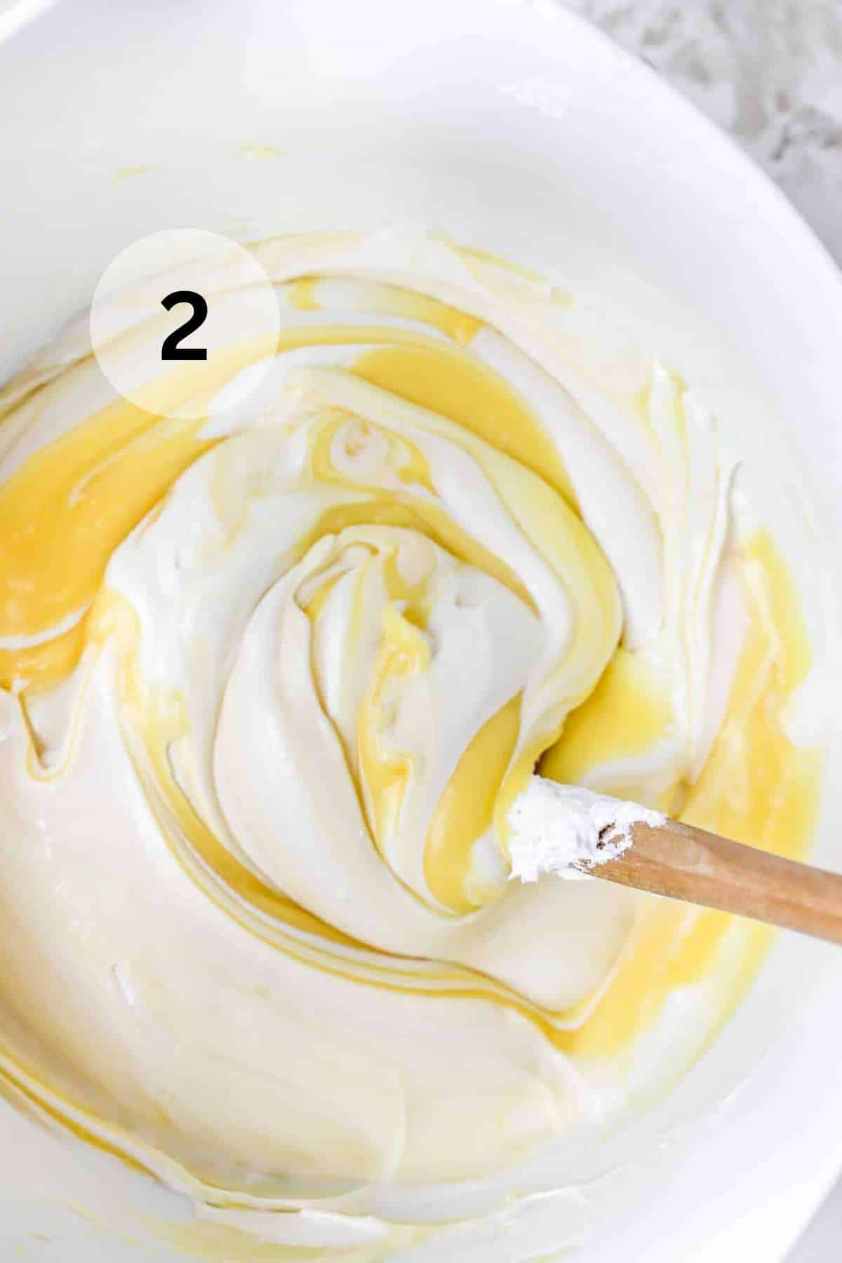 Stirring pudding mixture with cream cheese mixture and cool whip in a large bowl.