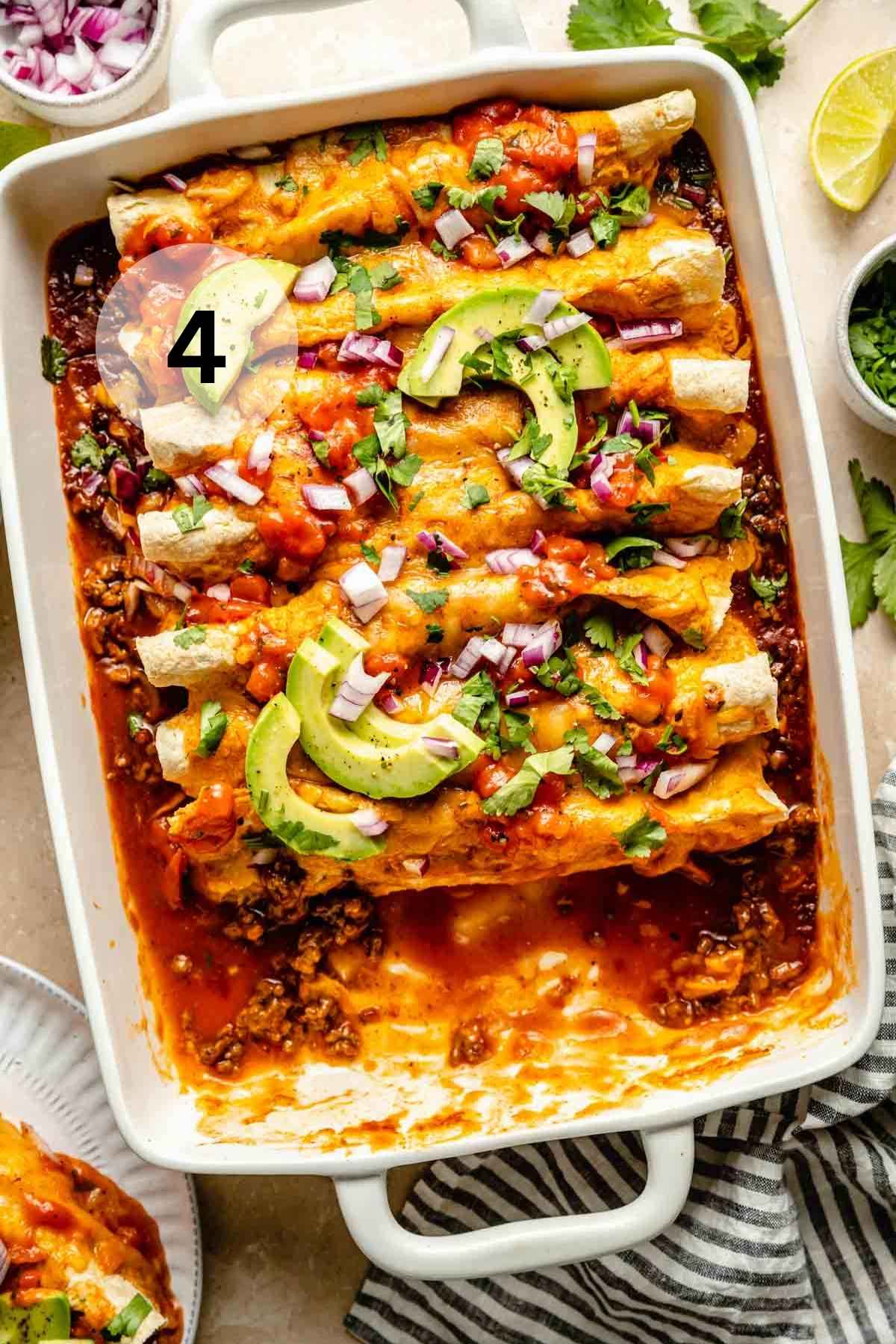 Cooked beef enchiladas in a white dish with a serving removed.