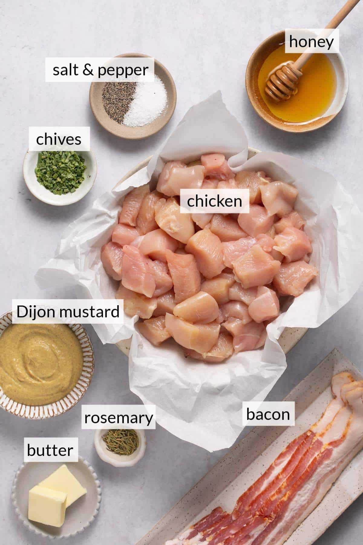 Uncooked chicken pieces, bacon, and bowls of honey, mustard and butter.