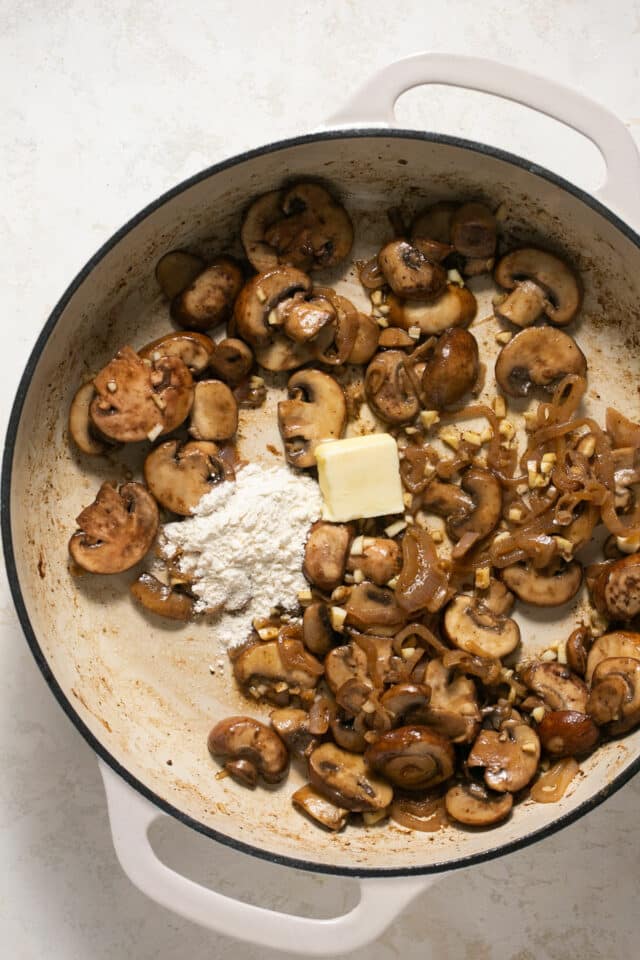 Adding butter and flour to cooked mushrooms.