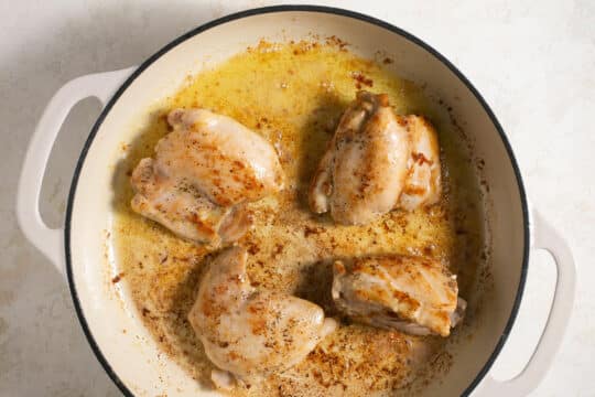 Seared chicken thighs in a large pot cooked in butter.