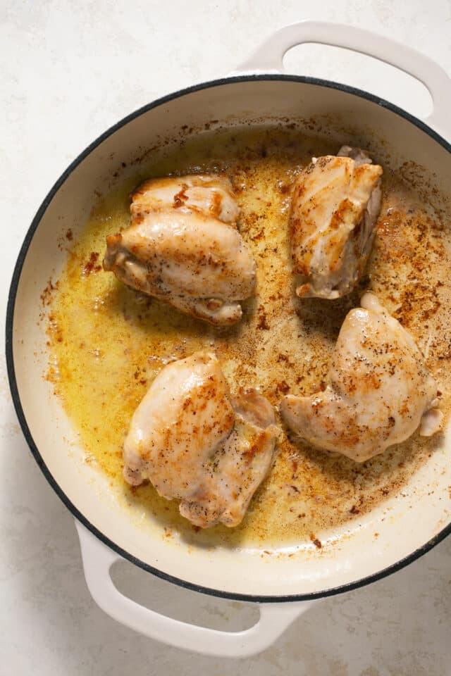 Seared chicken thighs in a large pot.