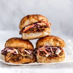 Three stacked pulled pork sliders made with coleslaw and pork.