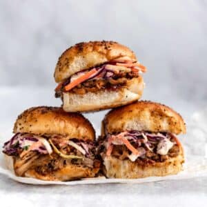 Three stacked pulled pork sliders made with coleslaw and pork.