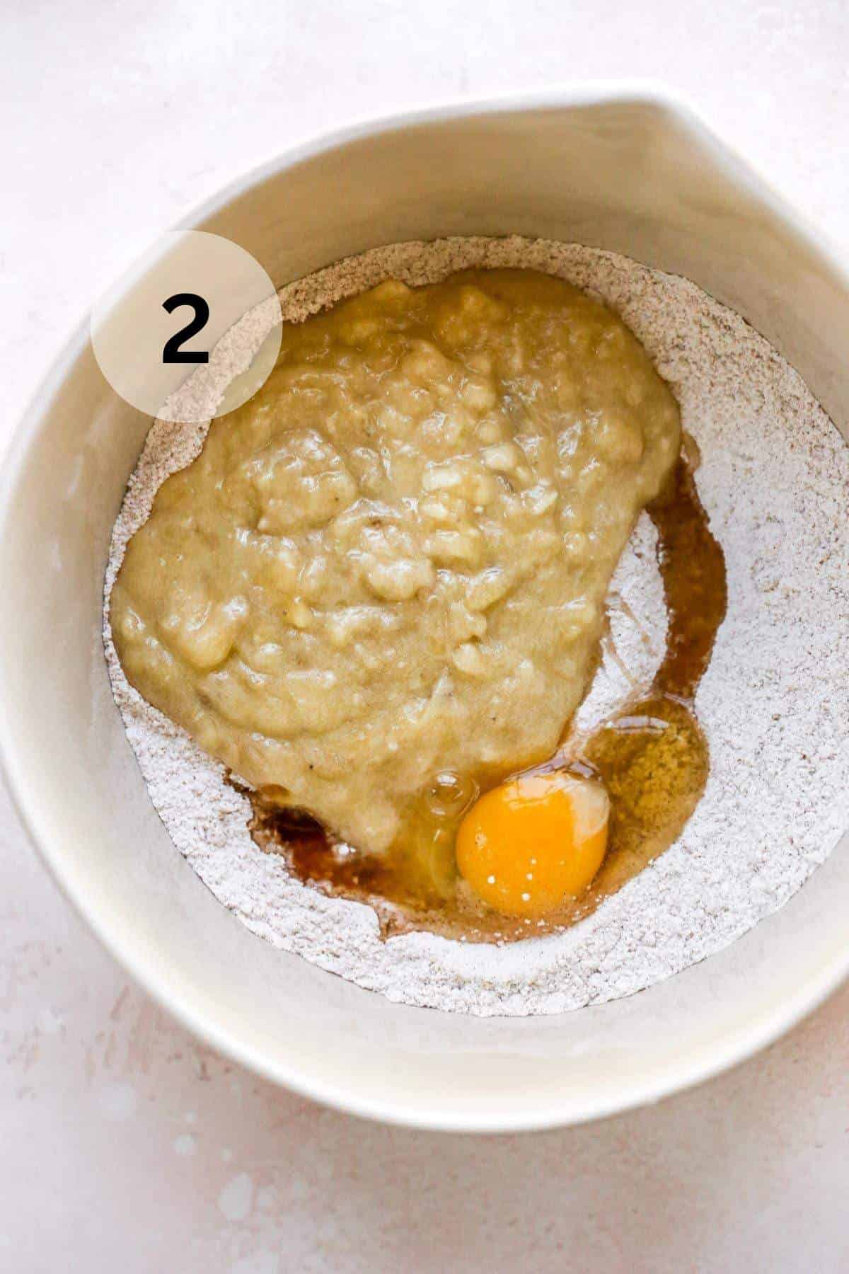 Mashed banana and egg added to dry mixture in a bowl.