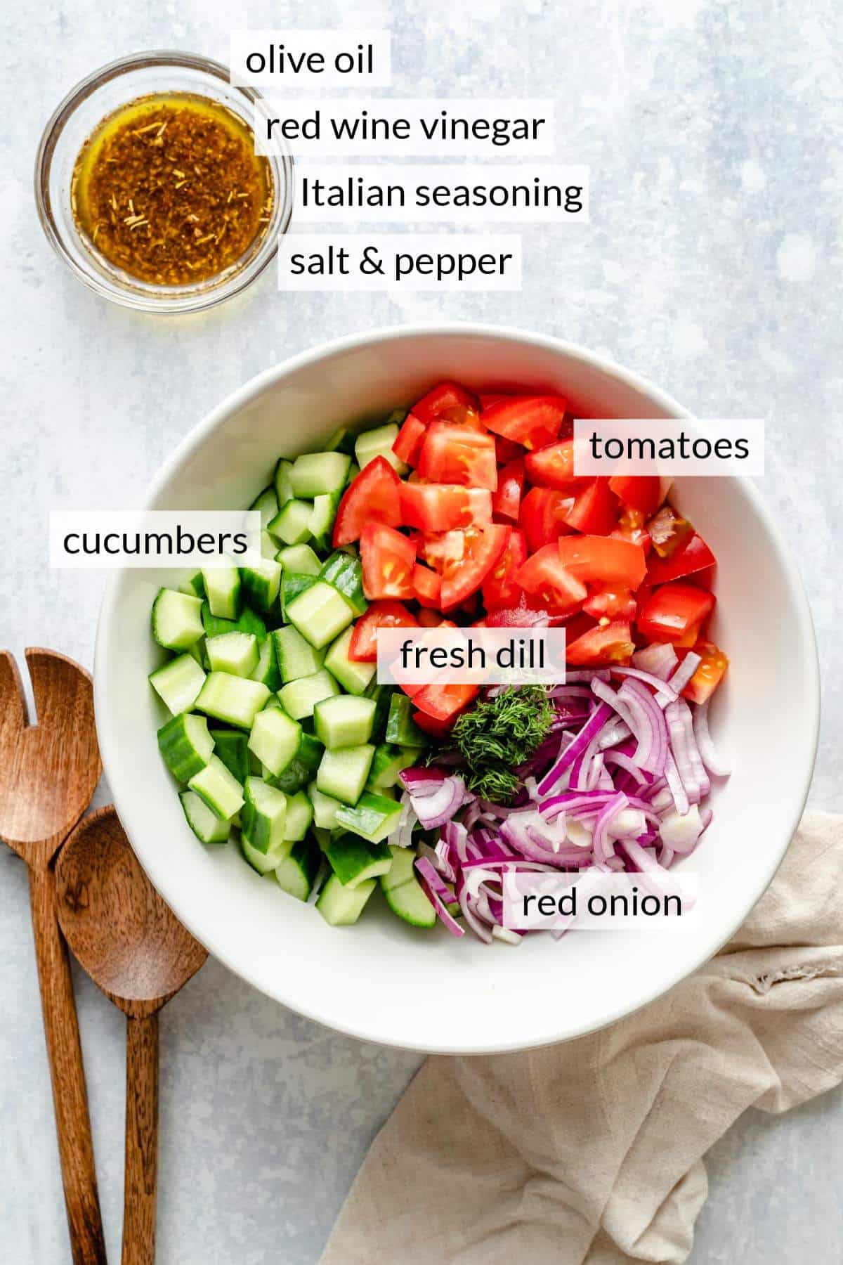 White bowl filled with chopped cucumber, tomato, red onion and dill.