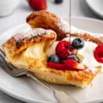 A dutch baby topped with berries and a drizzle of maple syrup.