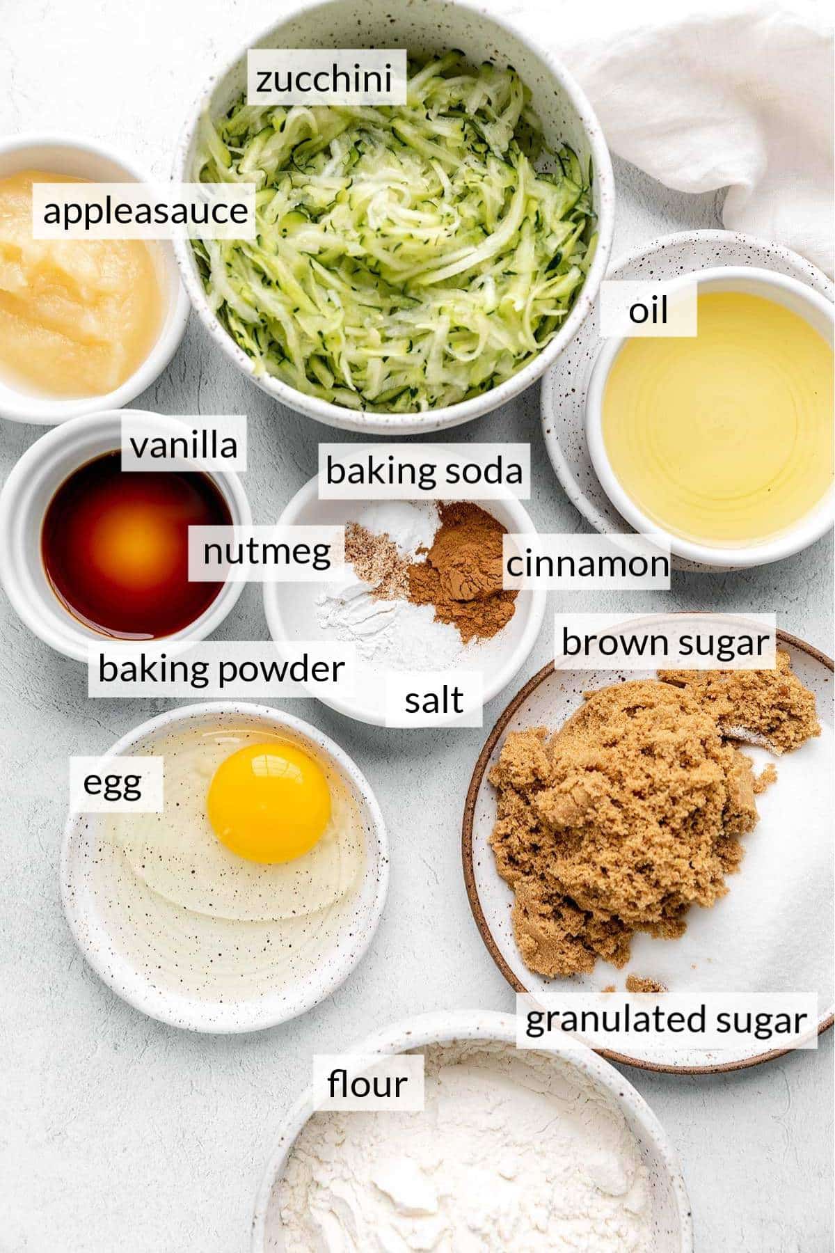 Bowls with zucchini, oil, applesauce, sugar and egg.