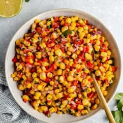 Corn salsa in a white bowl near a lime.