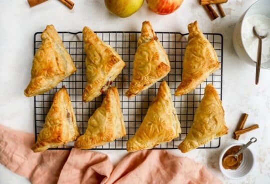 Baked apple turnovers on a wire rack.