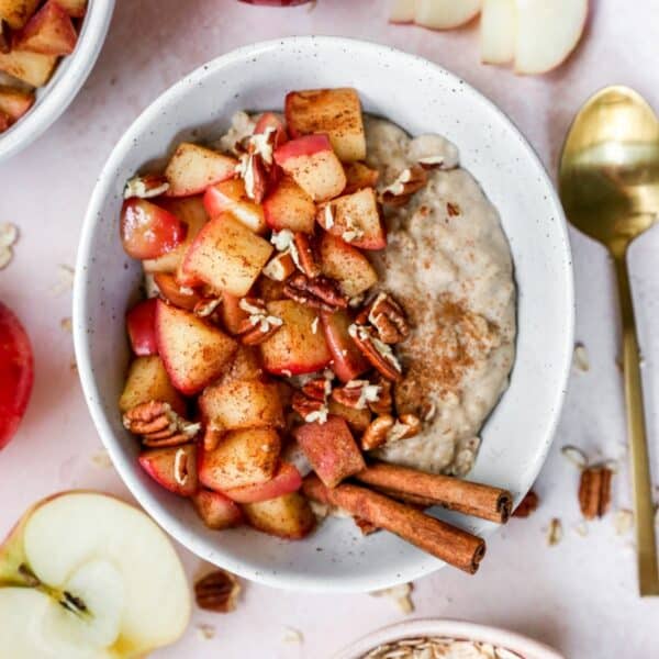 Apple cinnamon oatmeal topped with diced apple and cinnamon sticks.
