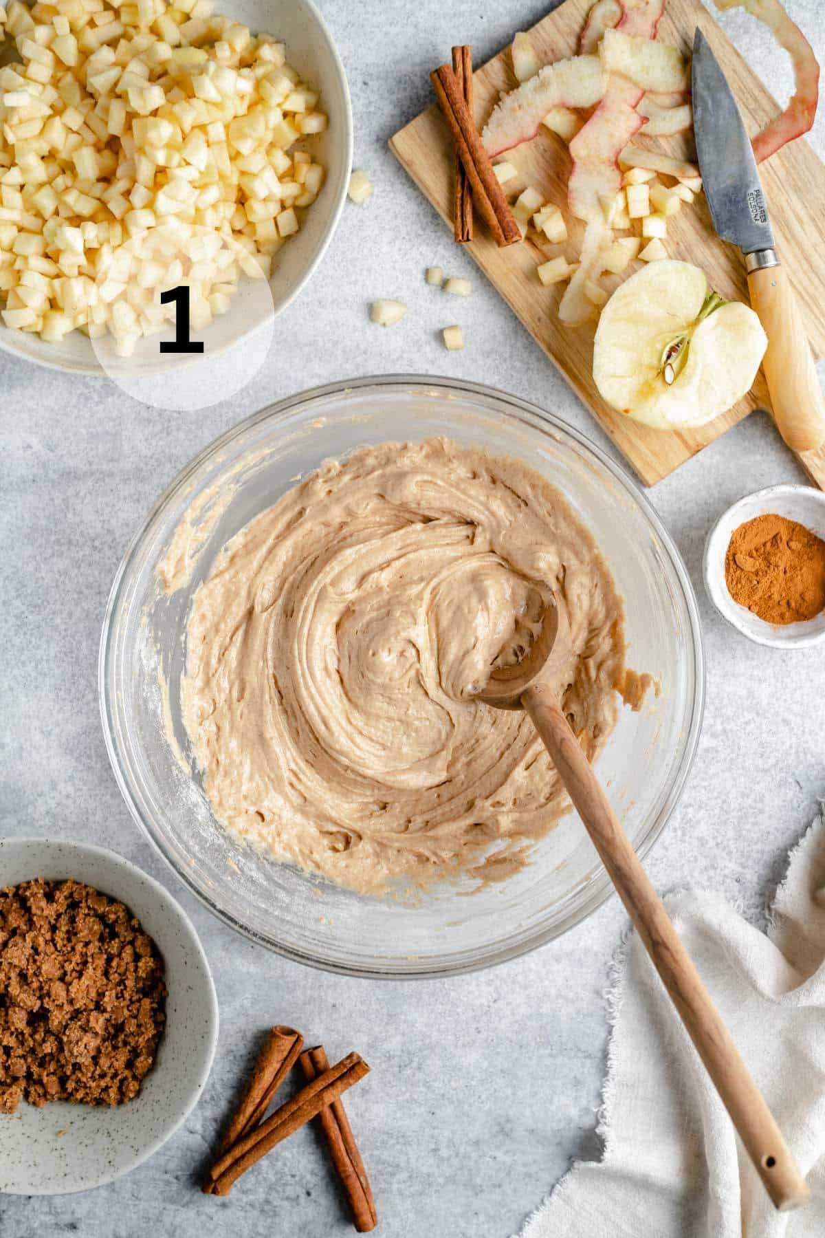 Using a wooden spoon to stir together wet and dry ingredients for apple coffee cake.