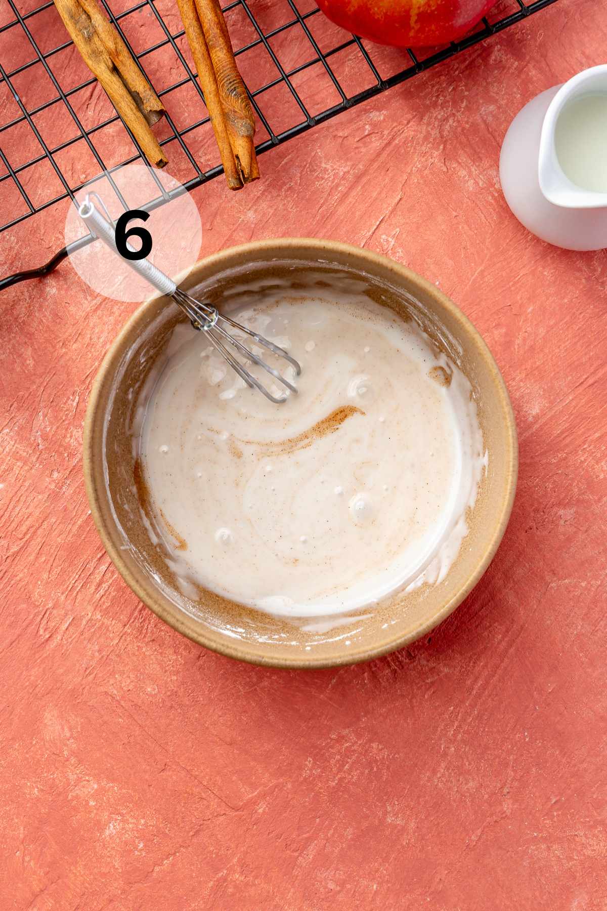 Whisking powdered sugar with milk and cinnamon in a small bowl.