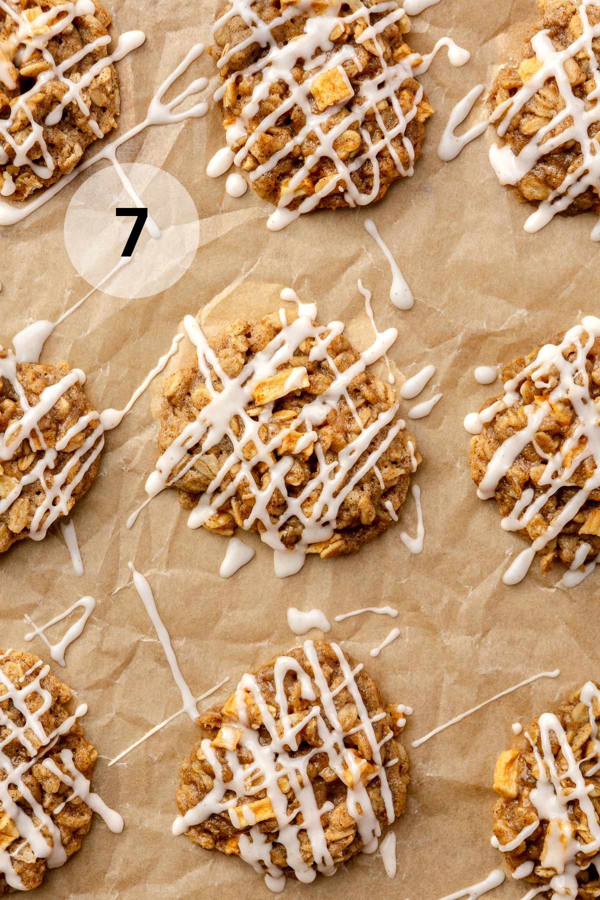 Icing drizzled over apple cookies on parchment paper.