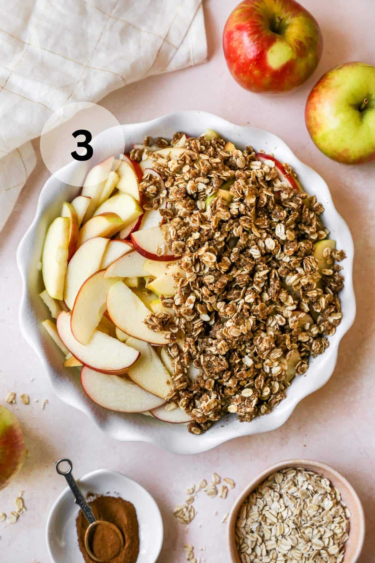 Topping sliced apples with oat mixture in a pie plate.