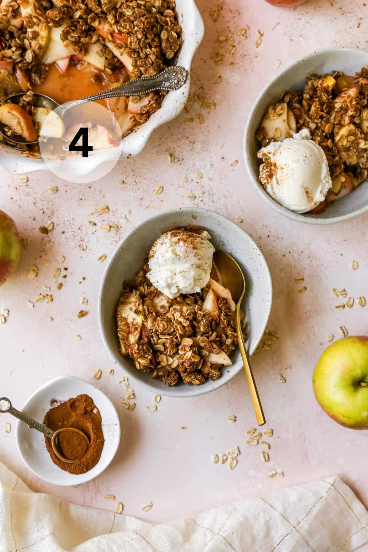 Apple crisp served in small bowls with vanilla ice cream.