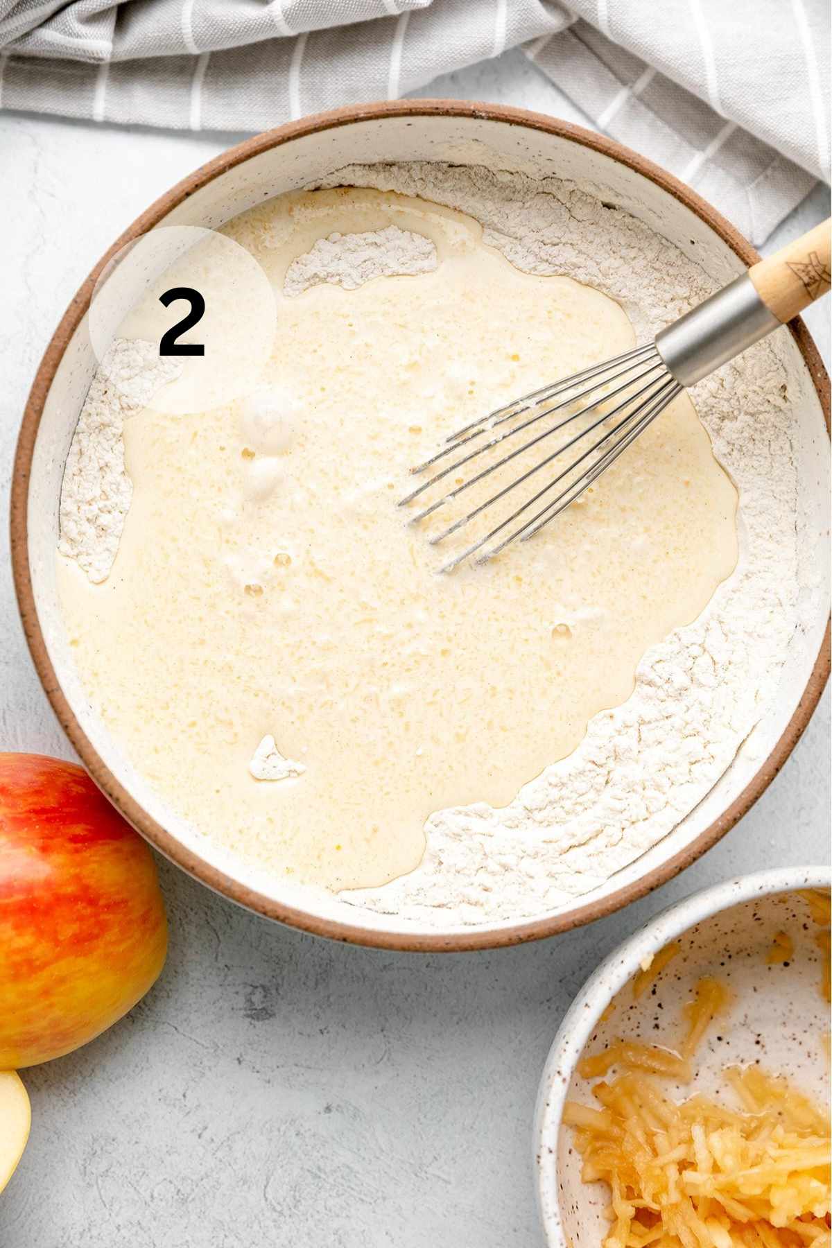 Whisking wet ingredients and dry ingredients in a large bowl.