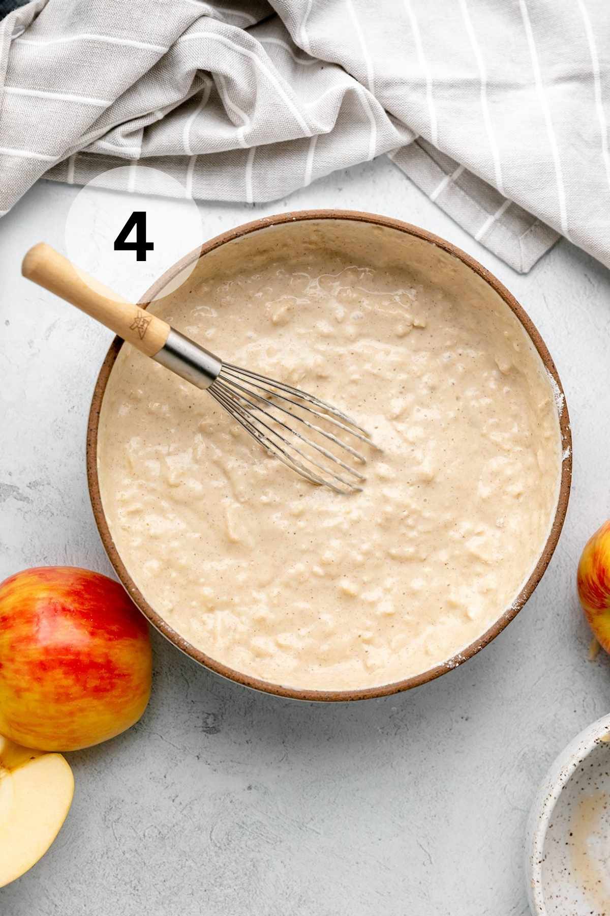 Whisk in a large bowl filled with apple pancake batter.