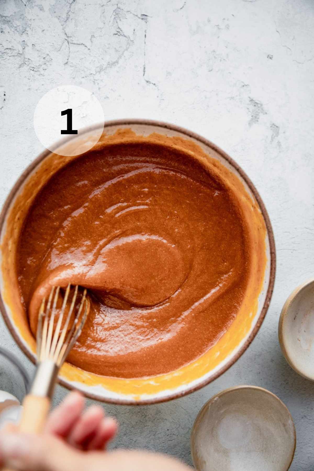 Using a whisk to mix pumpkin puree, eggs, sugar and water.