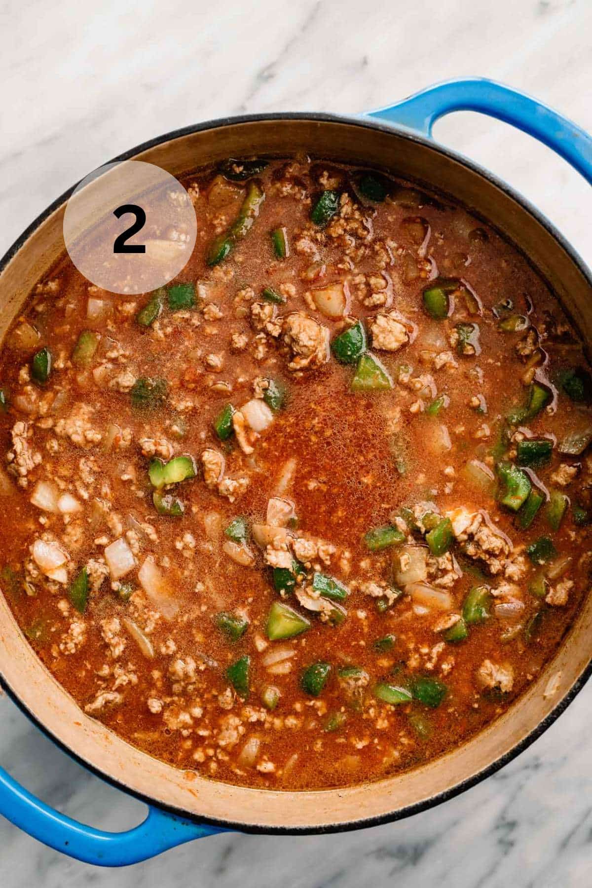 Chili simmering in a large blue dutch oven.