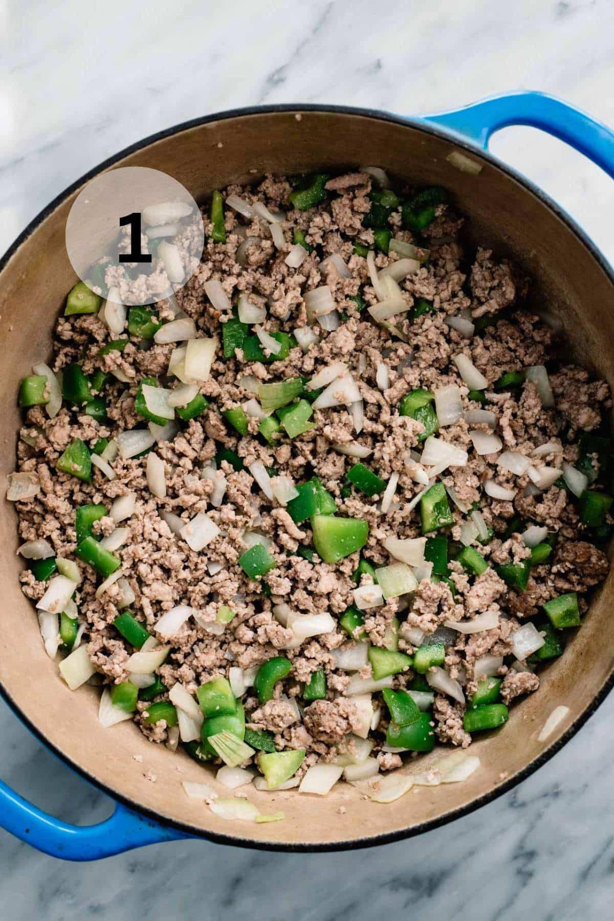 Browning meat with onion and bell pepper in a large pot.