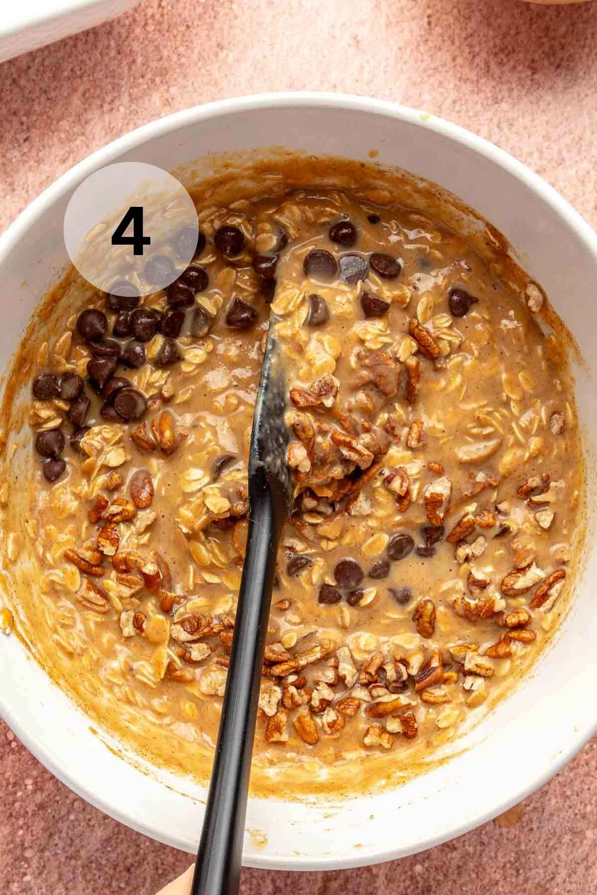 Stirring chopped pecans and chocolate chips into pumpkin oatmeal.