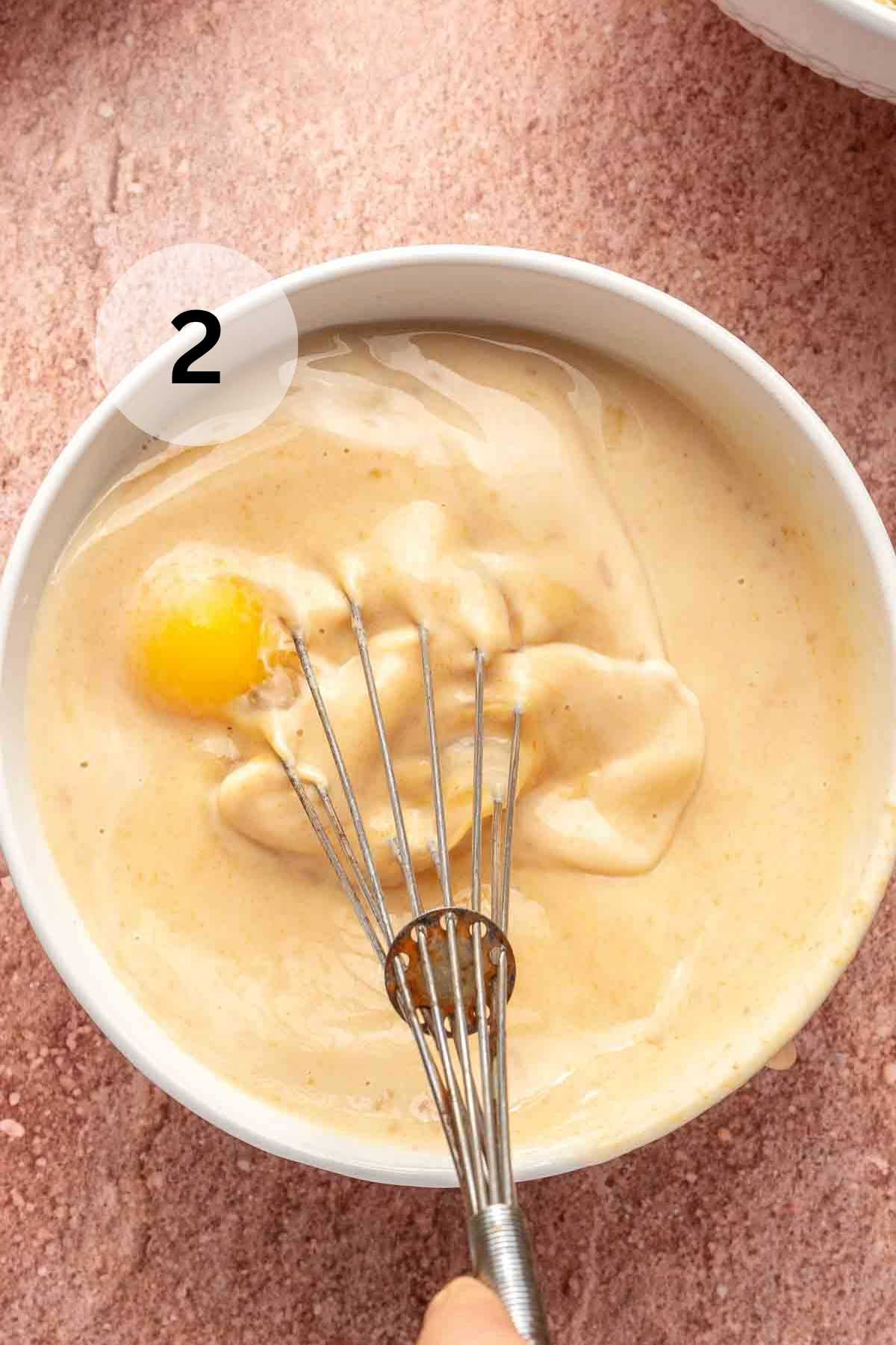 Using a whisk to combine eggs with milk and pumpkin.