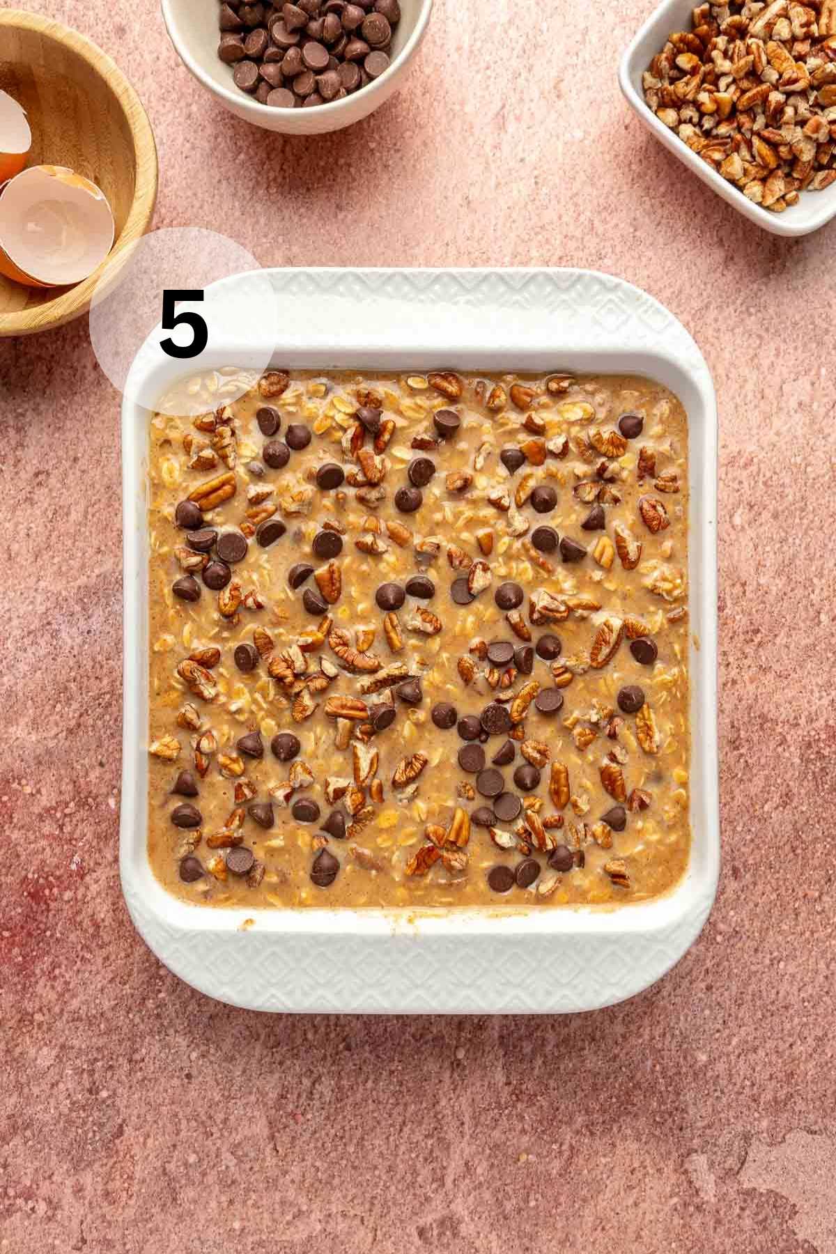 Topping oatmeal with chopped pecans and chocolate chips.