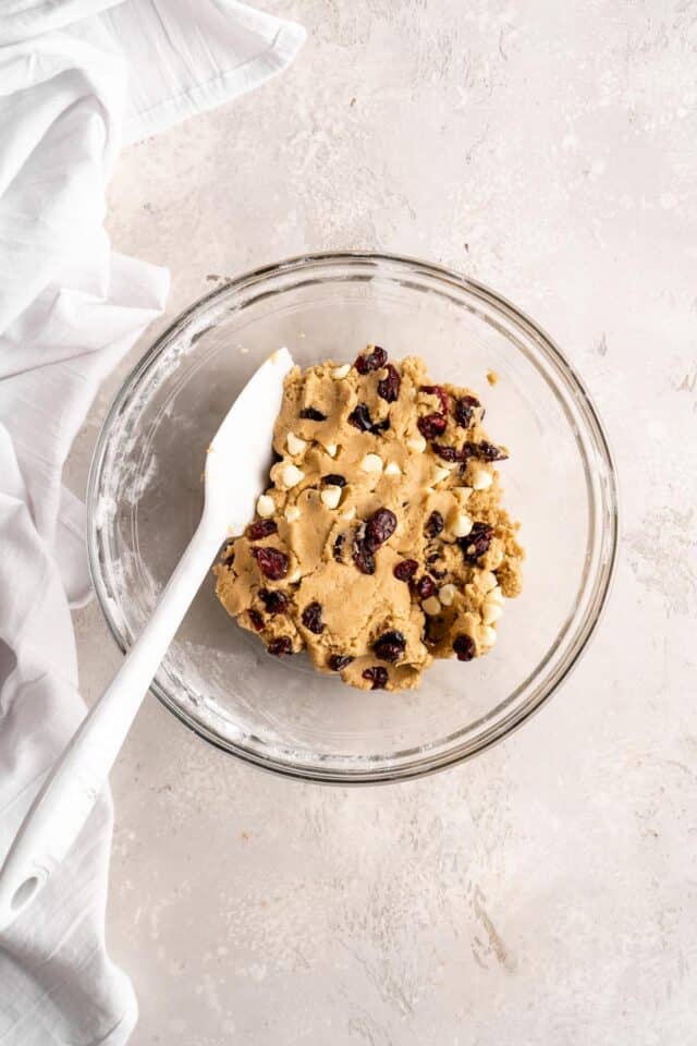 Stirring white chocolate chips and cranberries into cookie dough.
