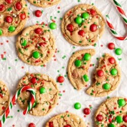 M&M Christmas cookies with sprinkles near candy canes.