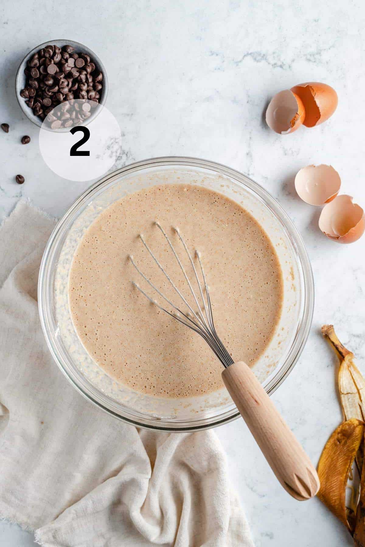 Banana waffle batter in a bowl with a whisk.