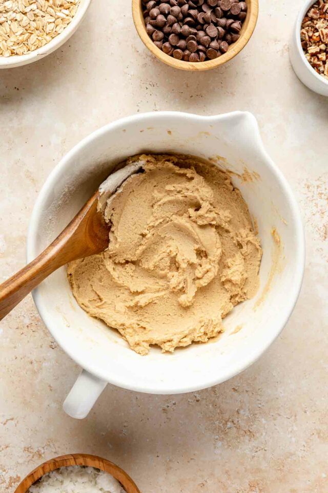 Using a wooden spoon to stir flour into cookie dough.