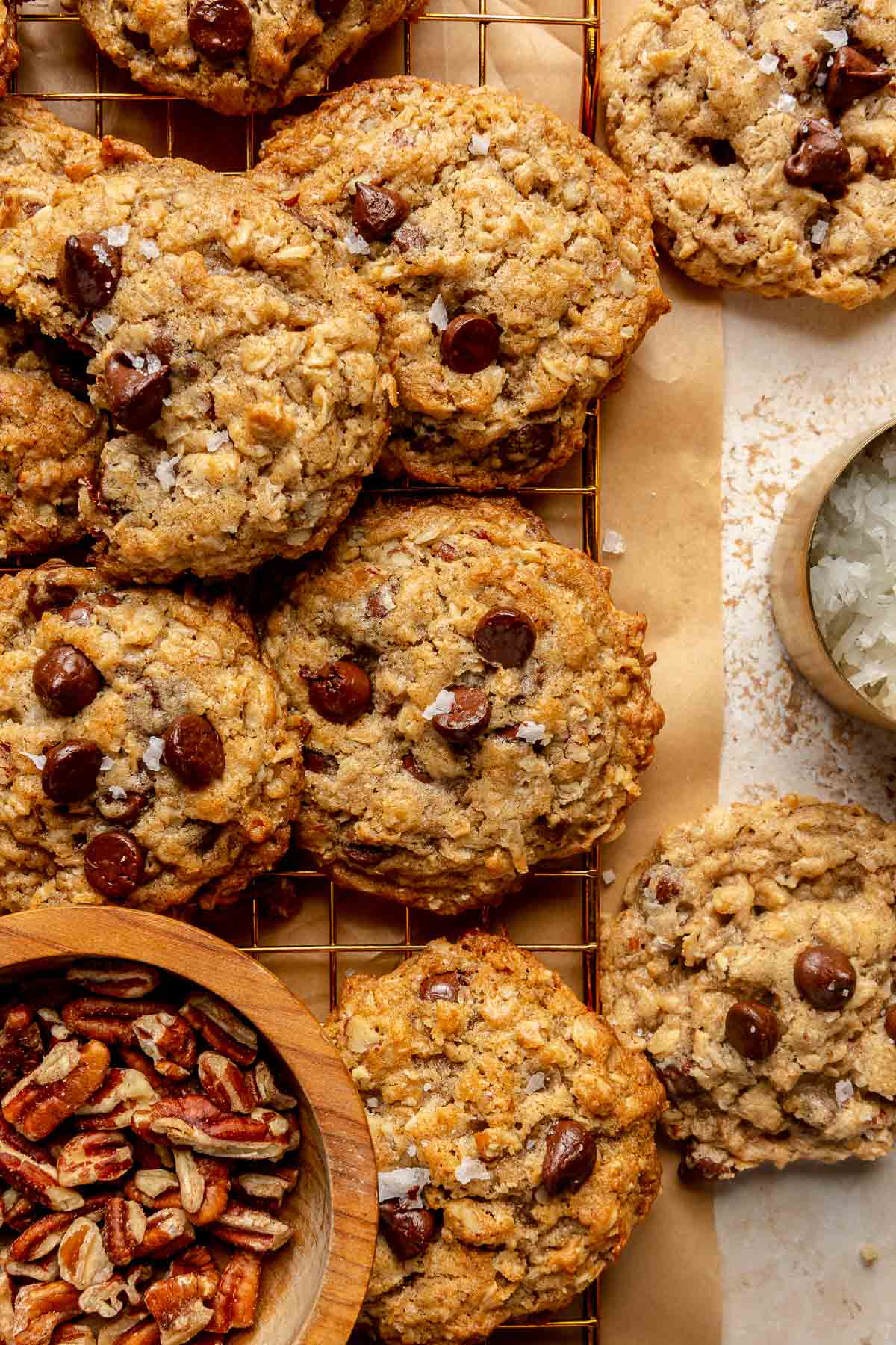 Cowboy cookies near a small bowl of shredded coconut and one with chopped pecans.