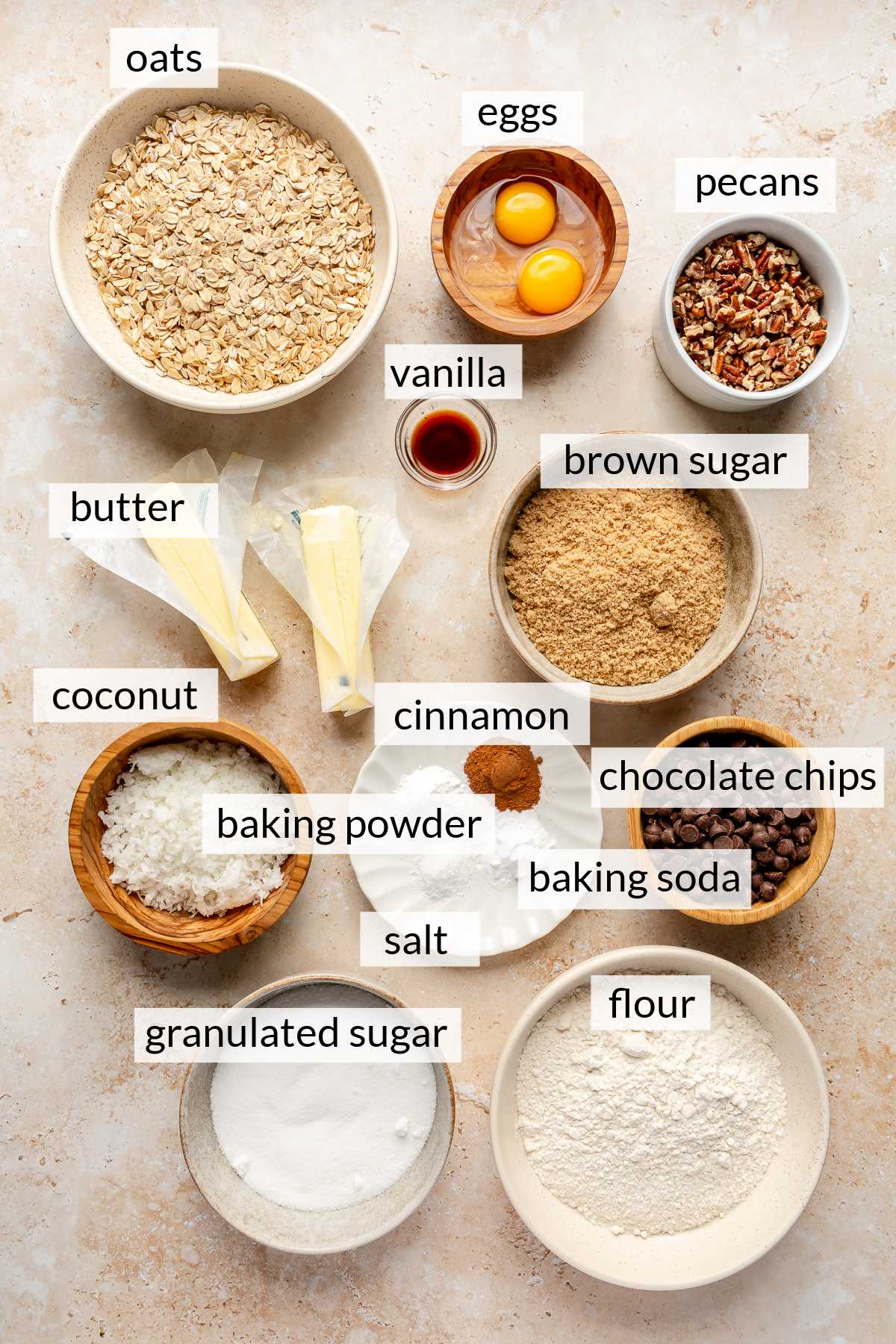 Flour, sugar, eggs, pecans, coconut, oats and vanilla divided into small bowls.