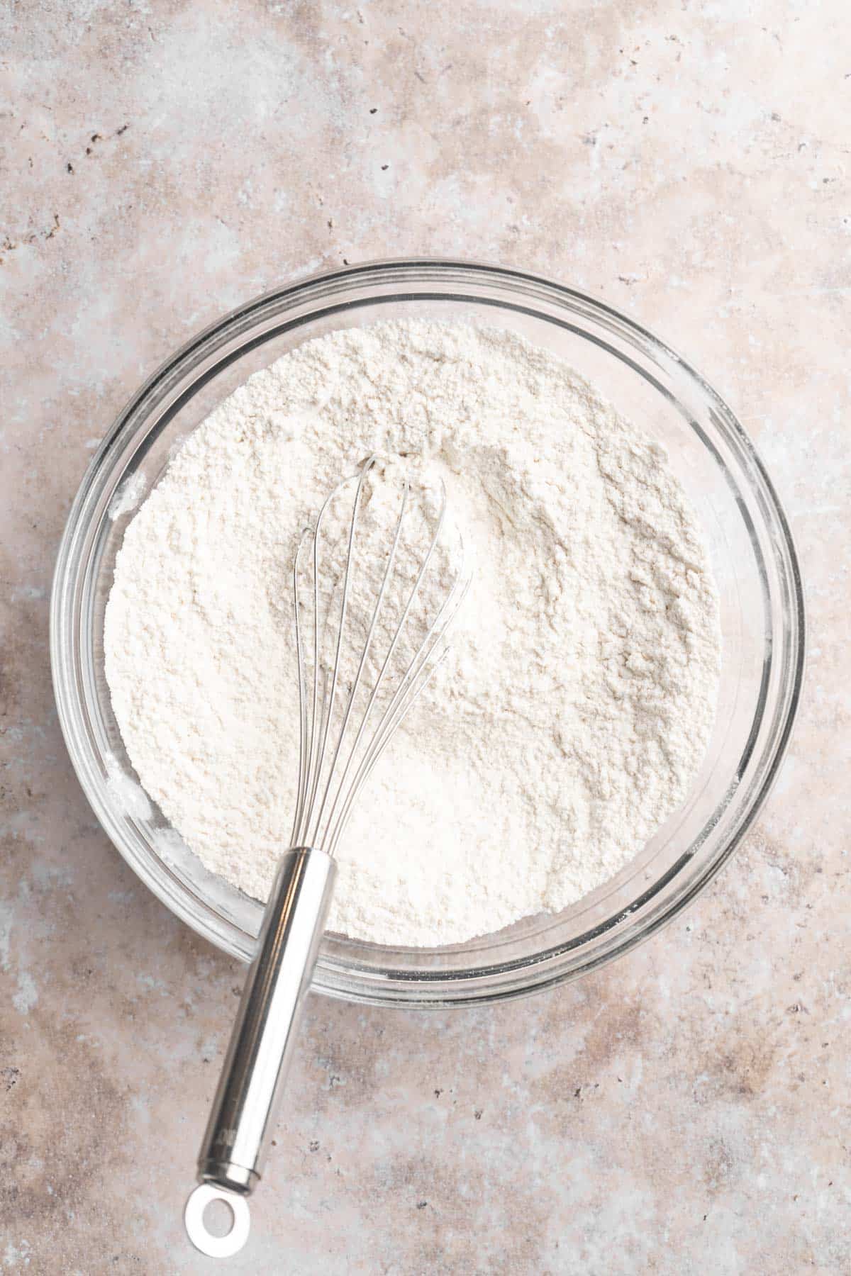 Whisking flour with baking powder in a large bowl.