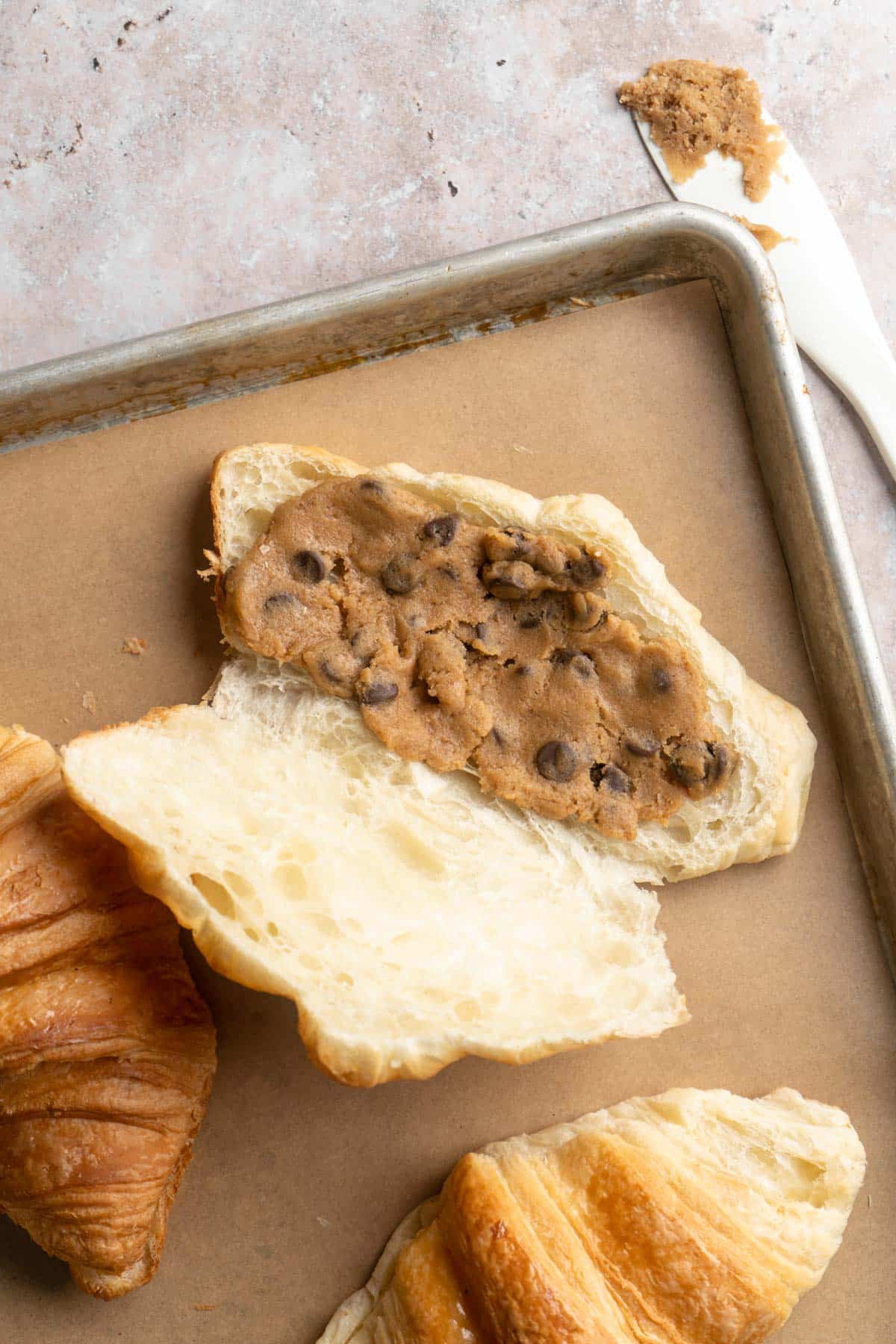 Adding chocolate chip cookie dough to the center of a croissant.