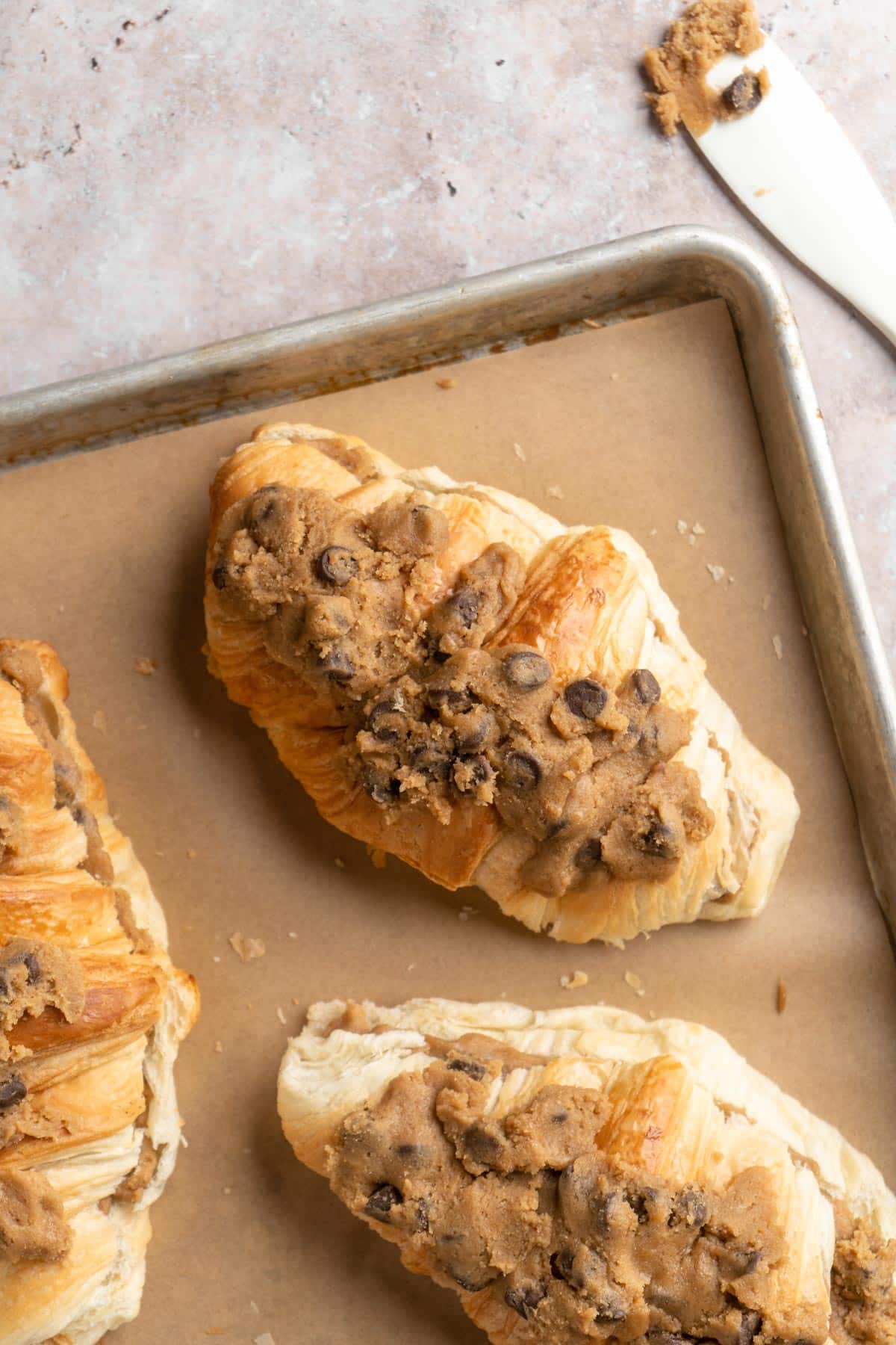 Croissants on a baking sheet topped with cookie dough.