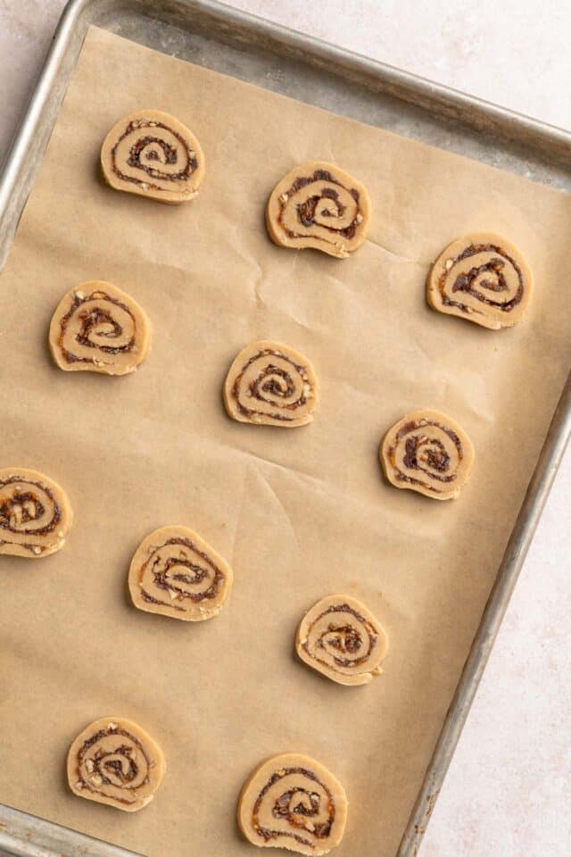 Sliced date pinwheel cookies on a sheet pan.