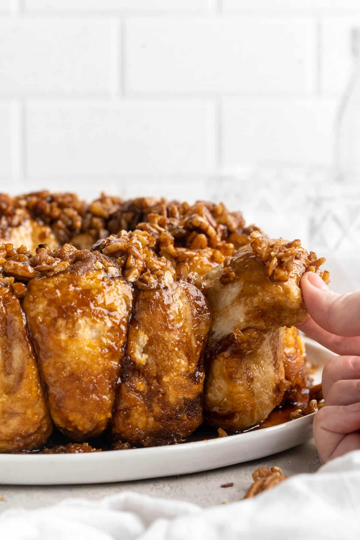 Hand pulling a piece of pull-apart monkey bread apart.