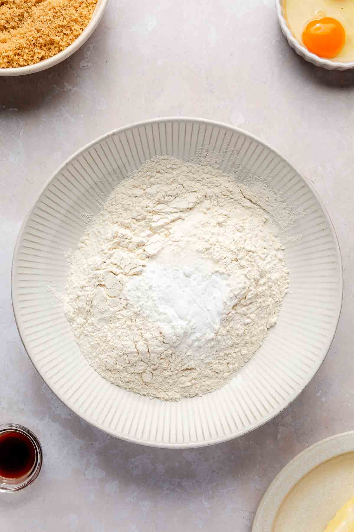 Flour, baking soda, baking powder and salt in a white bowl.