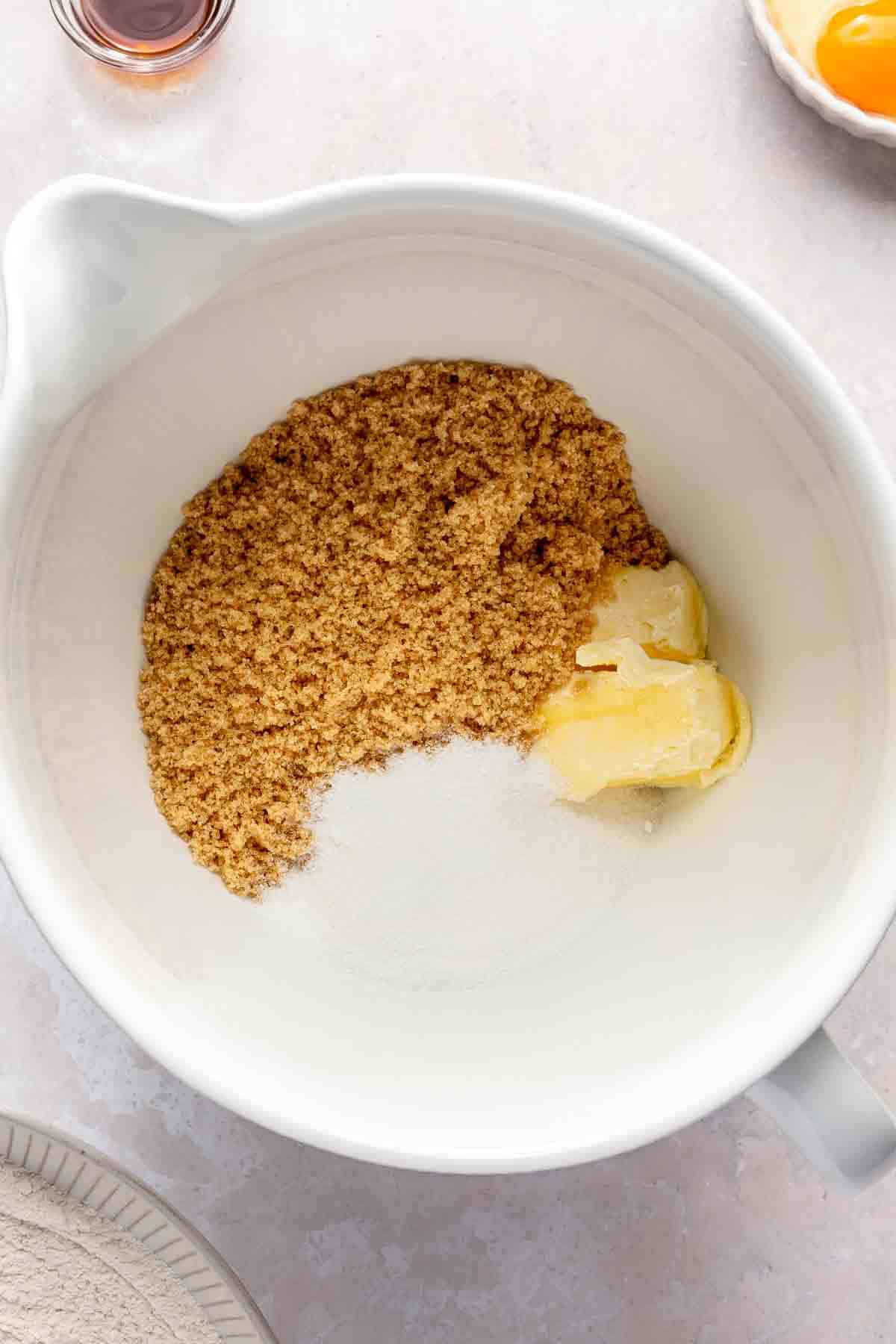 Butter and sugars in a white mixing bowl.